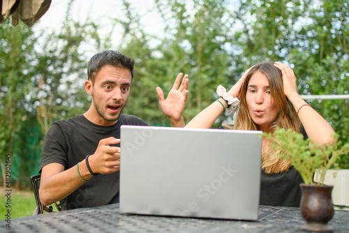 Emotions. Young caucasian couple with a surprised expression looking at their laptop.