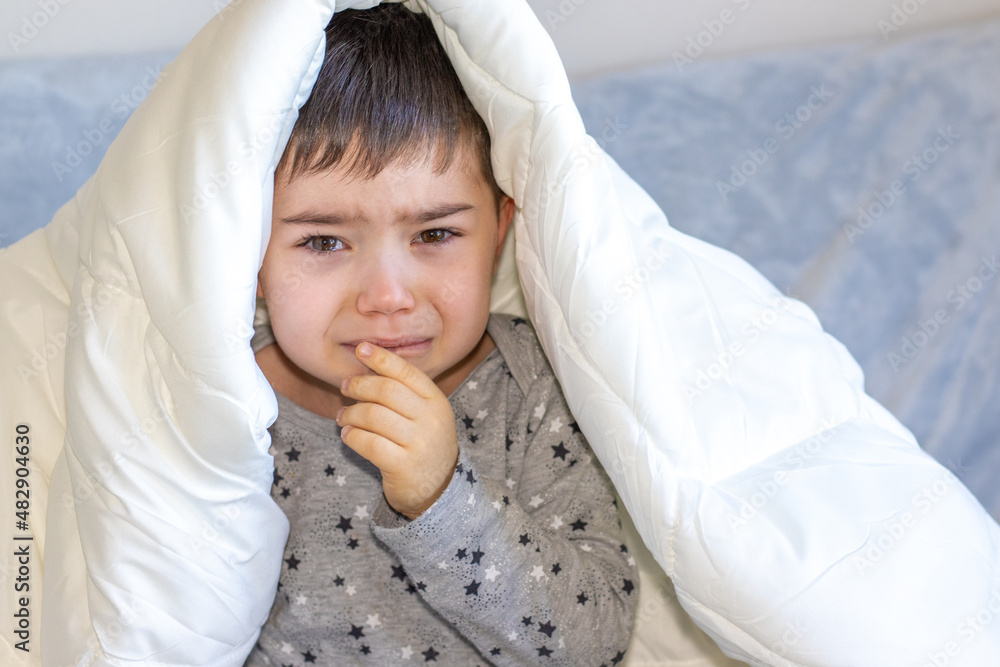 cute 4 years old boy is crying under a white blanket. little kids