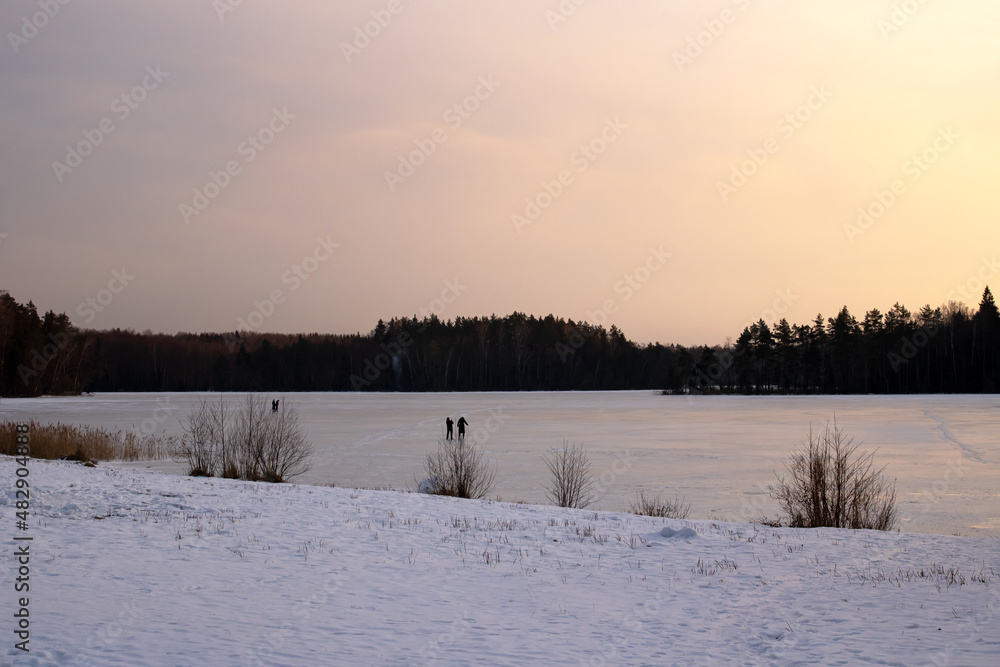 Snow-covered lake shore under ice at sunset Snow-covered lake shore under ice at sunset