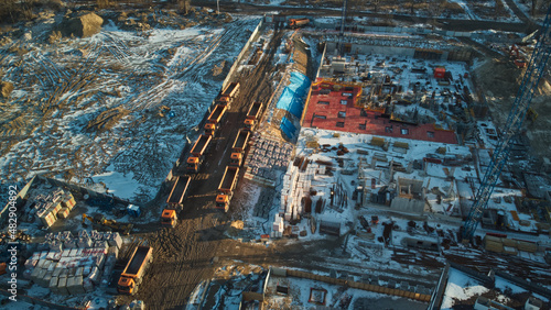 Two rows of trucks on the construction site of a residential building during the winter. Aerial view.  © Robert