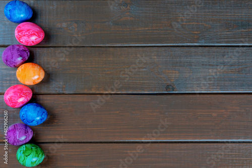 Colored easter eggs on a wooden background, top view, copy space