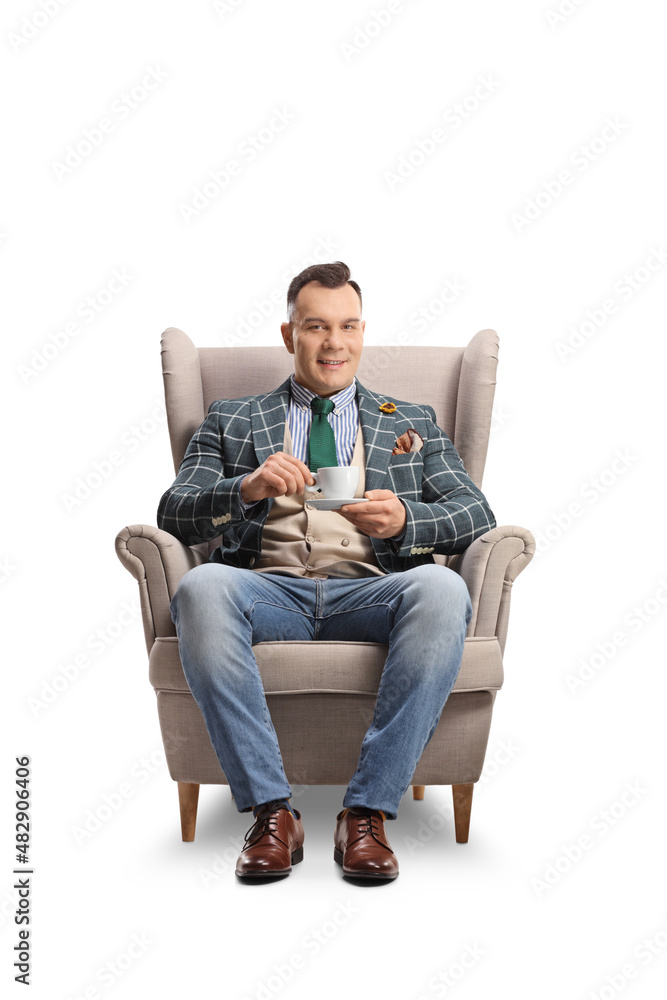 Fashionable man sitting in an armchair with a cup of espresso coffee