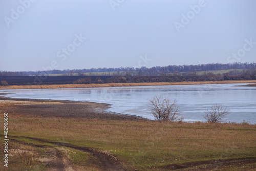 Bank of the river in early spring, the water is present unmelted ice. A small steppe river in late winter or early spring