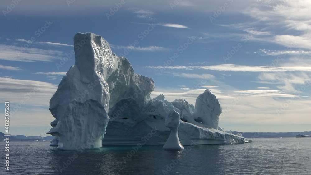 piękne i majestatyczne góry lodowe ukształtowane w fantazyjne formy pływające po morzu w pochmurny dzień - obrazy, fototapety, plakaty 