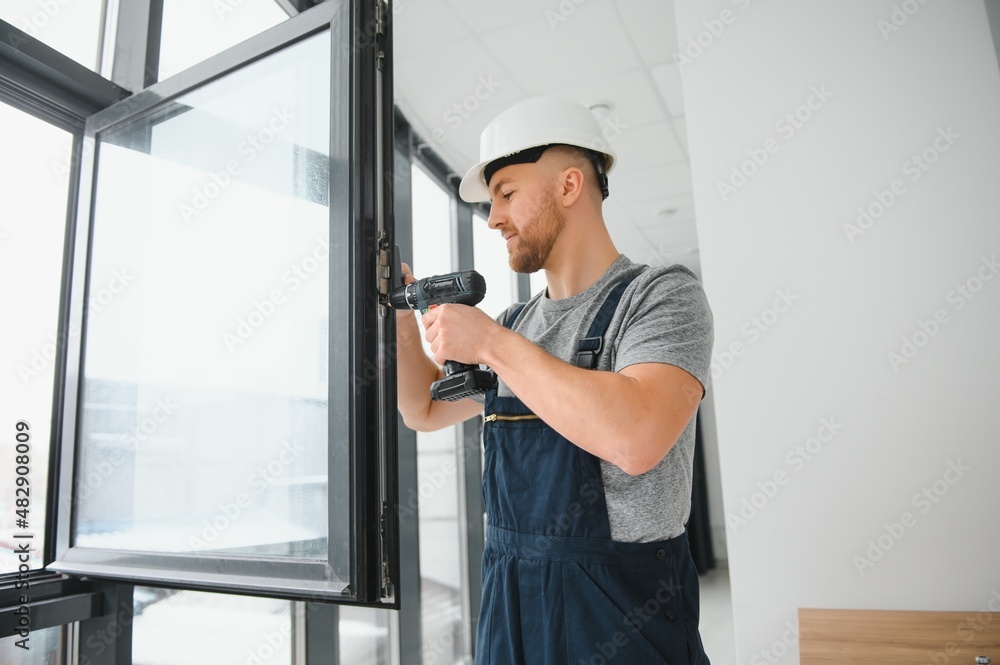 handsome young man installing bay window in new house construction site
