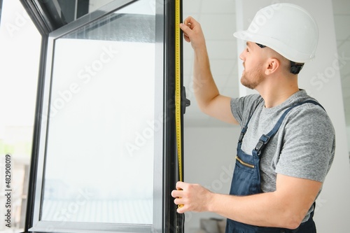 Construction worker repairing plastic window with screwdriver indoors, space for text. Banner design