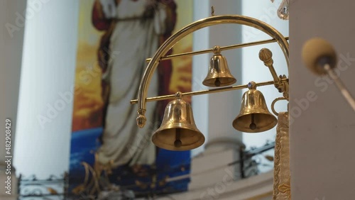 Small golden bells of various sizes hang on golden pendant in the interior of the church. Tintinnabulum hangs in the temple against the backdrop of fresco. photo