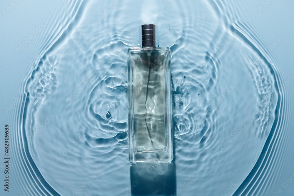 Perfume bottle on blue water wavy background. Fresh sea fragrance concept. Pure and chilly.