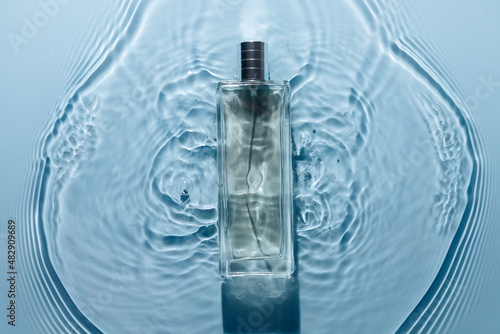 Obraz na płótnie Perfume bottle on blue water wavy background. Fresh sea fragrance concept. Pure and chilly. w salonie