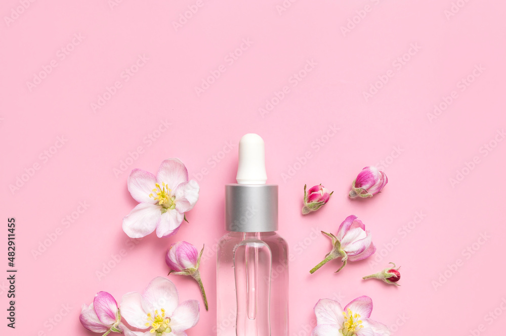 Clean glass cosmetic bottles with dropper, delicate spring flowers on pink background flat lay top view. Spring concept of natural organic cosmetics, beauty herbal product spa aroma oil. Mockup Clean glass cosmetic bottles with dropper, delicate spring flowers on pink background flat lay top view. Spring concept of natural organic cosmetics, beauty herbal product spa aroma oil. Mockup