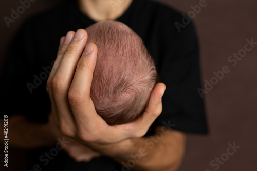 the head of a newborn in the palm of the father. small head of newborn