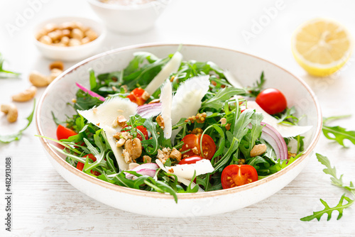 Fresh vegetable salad with arugula, tomato, onion, parmesan cheese and cashew nuts