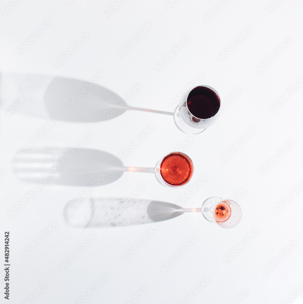 Glasses of wine with big shadows on light background. Festival time. Creative minimal concept lay out with top view. Flat lay. Glasses of wine with big shadows on light background. Festival time. Creative minimal concept lay out with top view. Flat lay.