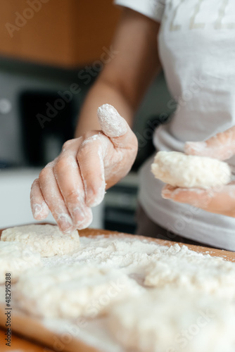 Women's hands mold delicious cheesecakes. Women's hands with flour close-up.