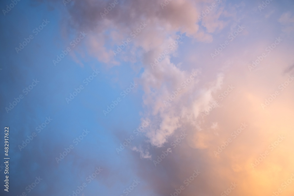 Dramatic moody sunset landscape with puffy clouds lit by yellow setting sun and blue sky. Dramatic moody sunset landscape with puffy clouds lit by yellow setting sun and blue sky.