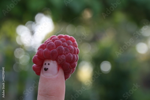 Red raspberry fruit smiley face on finger