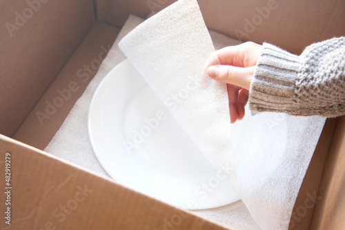 фотографія Woman packing white dishes away with white foam sheets