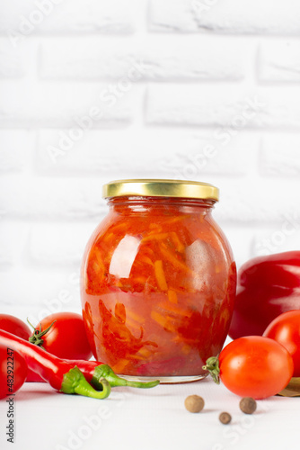 Glass jars with canned vegetables, lecho on white background. red canned, canned lecho in a glass jar