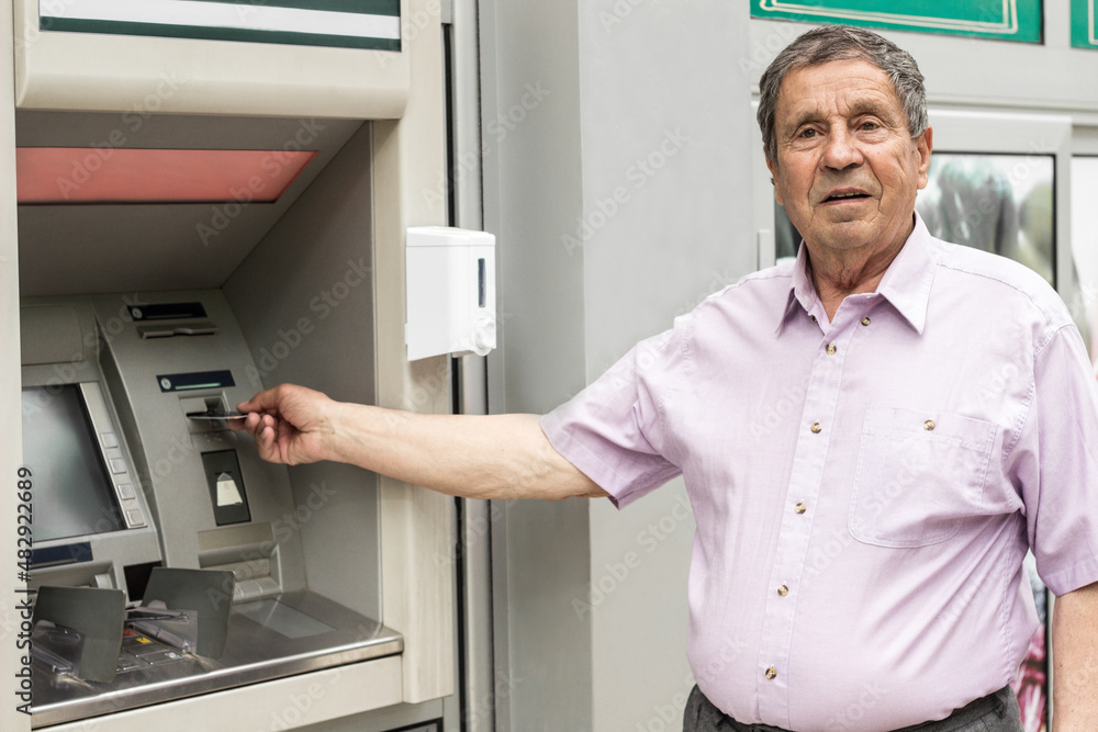 Senior man inserting credit card to ATM
