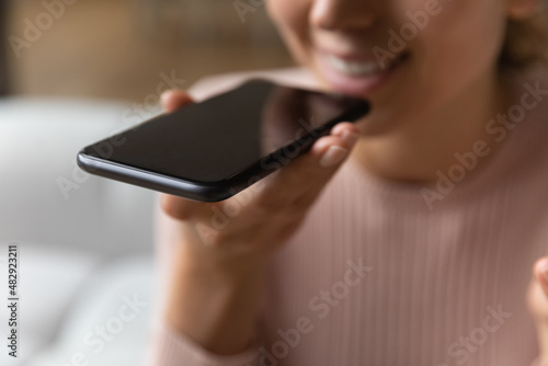 Foto Close up female hand holds smartphone near mouth using speakerphone, send audio
