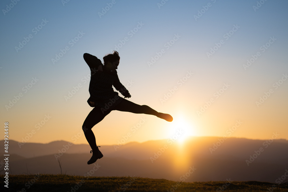 silueta de chica dando patada al atardecer silueta de chica dando patada al atardecer