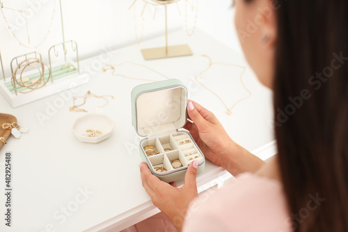 Woman with jewelry box on table with stylish accessories