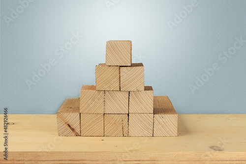 Wooden cubes stacked in the form of a pyramid without graphics on the background of a textured gray wall  the concept of business growth and teamwork  a symbol of leadership  a template for design