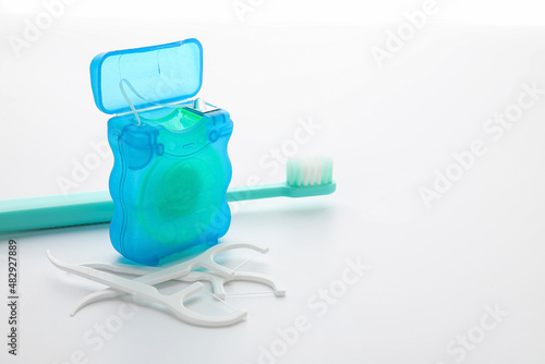 Dental floss with toothpicks and brush on white background