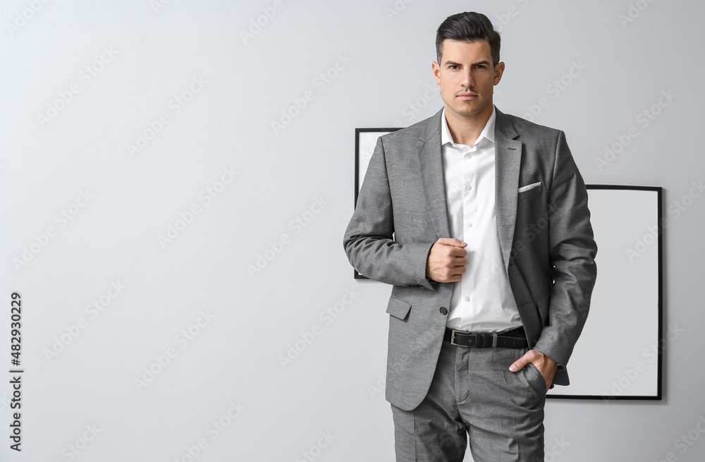 Handsome man in formal suit posing near grey wall Handsome man in formal suit posing near grey wall