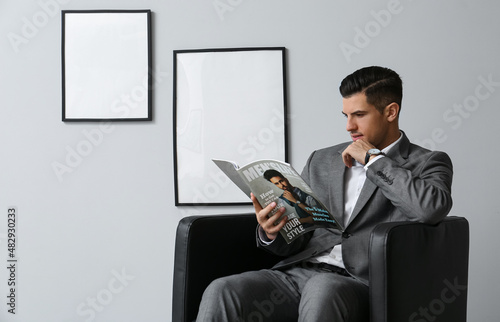 Fashionable man reading mag...