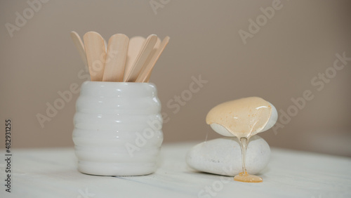 depilation and beauty concept - sugar paste or wax honey for hair removal with wooden wax sticks