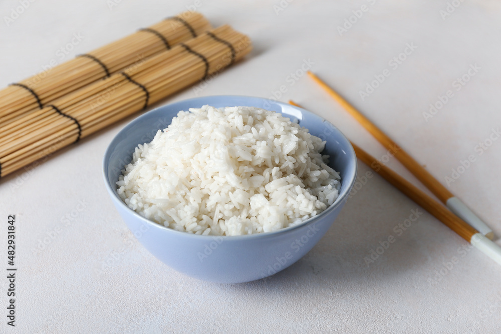 Bowl with tasty boiled rice and chopsticks on light background, closeup Bowl with tasty boiled rice and chopsticks on light background, closeup