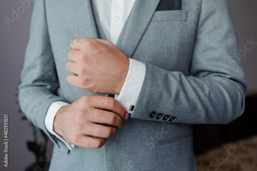 A groom fastening a cuff-link on the shirt. Men fastening a cufflink on their shirt