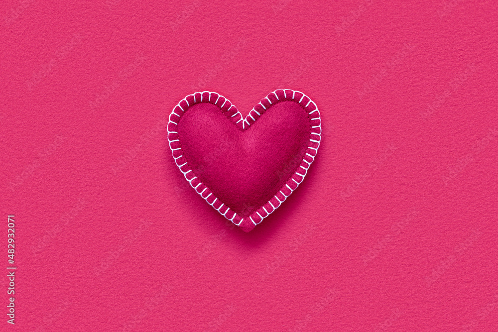 Soft handmade felt heart on red felt background Soft handmade felt heart on red felt background