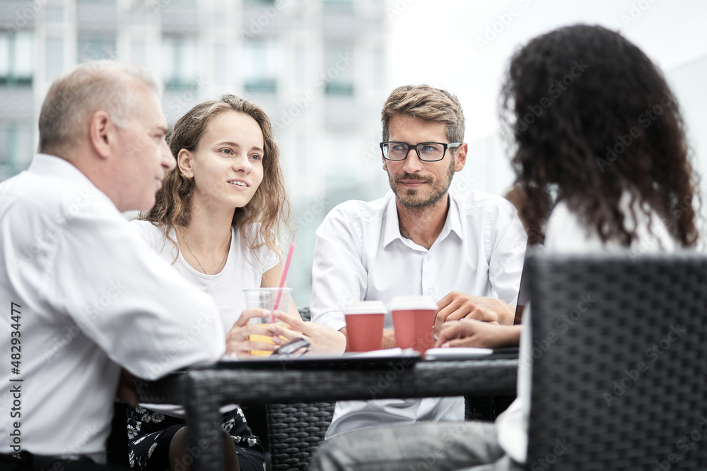 Fototapeta premium Smiling colleagues working together developing business strategy for their next project. Young casually dressed business people having discussion on sunny terrace. Modern job in comfortable conditions