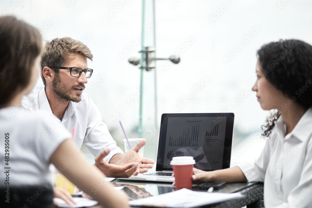 Fototapeta premium Smiling colleagues working together developing business strategy for their next project. Young casually dressed business people having discussion on sunny terrace. Modern job in comfortable conditions