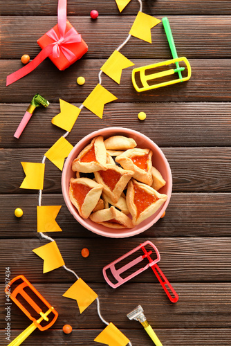 Hamantaschen cookies and rattles for Purim holiday on wooden background