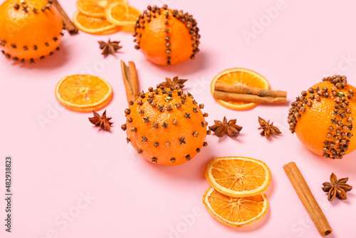 Handmade Christmas decoration made of tangerines with cloves on pink background, closeup © Pixel-Shot