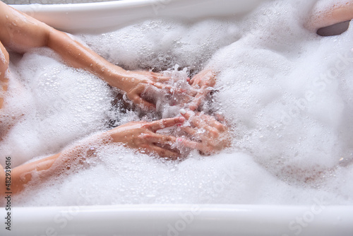 Close up top view of the hands of a couple in love taking a bath together with white foam.