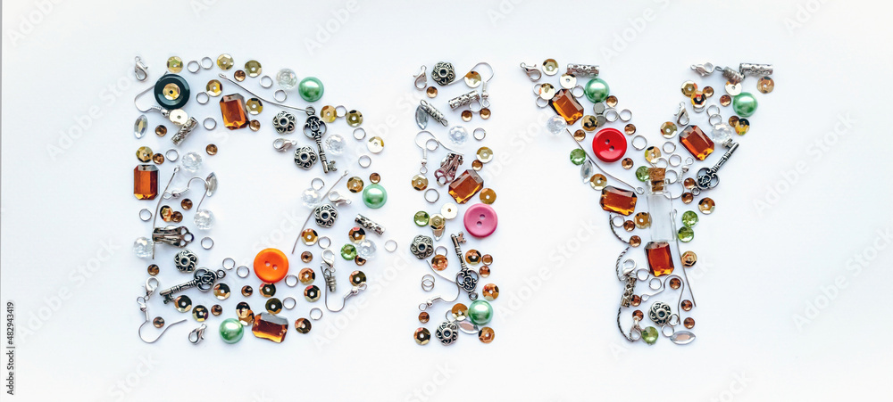 Diy lettering collected from handmade tools such as buttons, ear wires, locks, sequins, pendants on a white background. Craft and hobby concept Diy lettering collected from handmade tools such as buttons, ear wires, locks, sequins, pendants on a white background. Craft and hobby concept