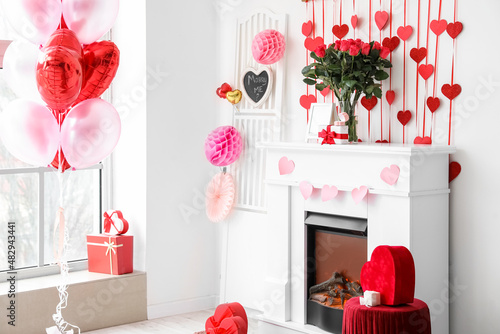 Bouquet of flowers, gift box and engagement ring on mantelpiece in light room decorated for Valentine's day