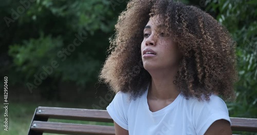 Sadness mixed race woman feeling chest hurt treason broken heart lost love relationship problem close up. Upset female with closed eyes suffering loneliness solitude grief heartbroken on bench park photo