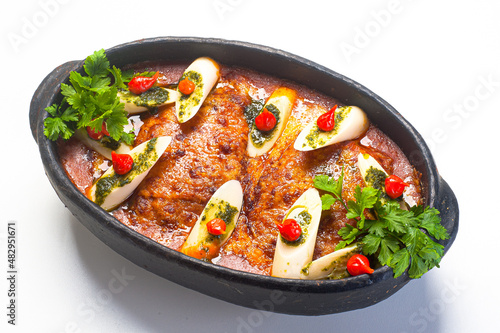 lasagna served in a clay pot with hearts of palm, pesto sauce and red pepper