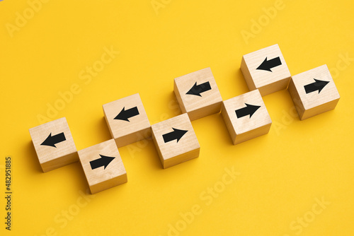 Wooden cubes with arrows moving in opposite directions. Concept of competition, diversity, confrontation or confrontation. photo