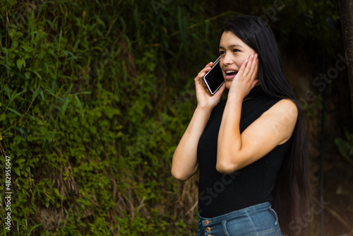 Una mujer latina emocionada  con un teléfono inteligente y lee buenas noticias, se siente feliz, se ve encantada y recibió una oferta increíble. Ganó la lotería, consiguió el trabajo soñado, celebre e photo