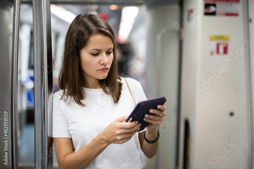 Portrait of female passenger using tablet in subway wagon