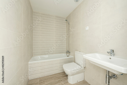 Newly renovated conventional toilet with white earthenware toilets and cream-colored tiles