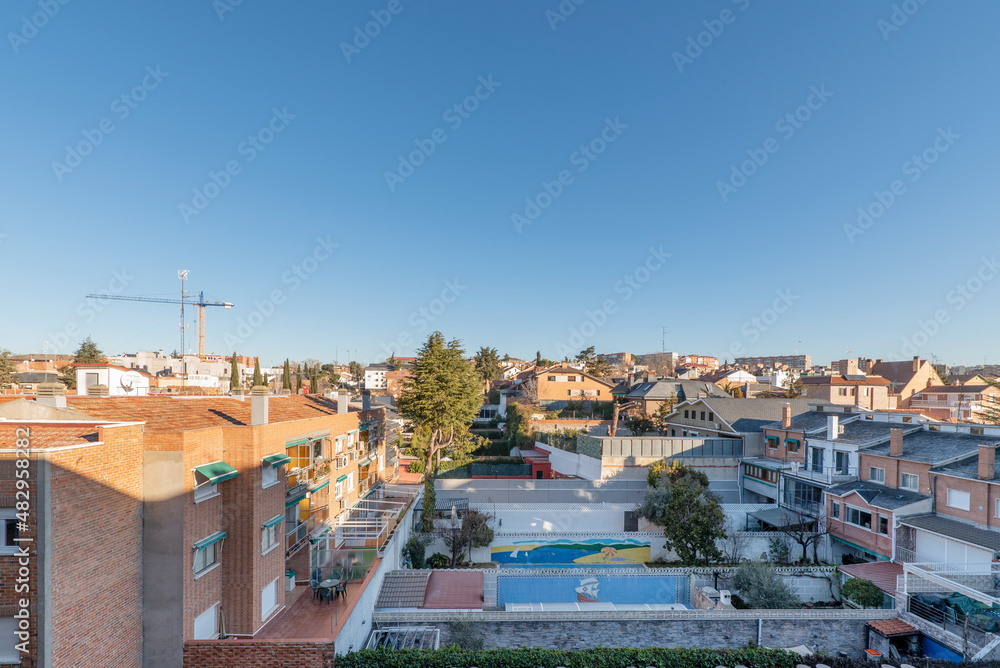 Views of residential single family home rooftops with pools and trees in the early morning