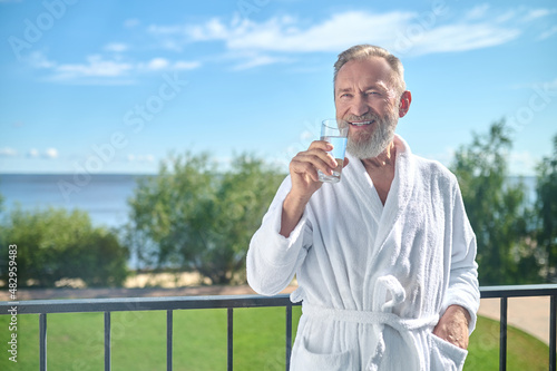 Pleased vacationer drinking a glass of water photo