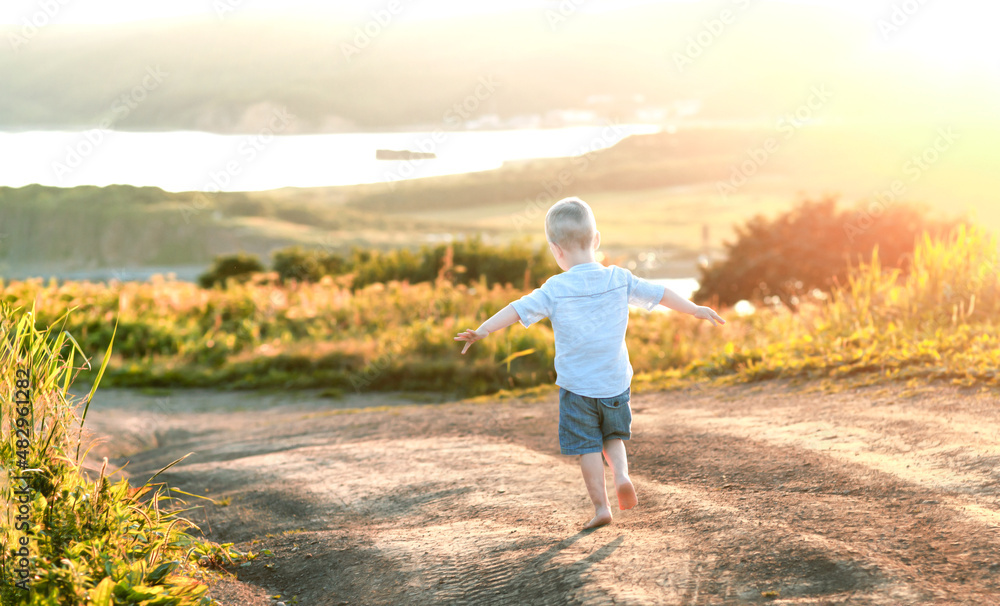 little boy at sunset runing barefoot along the road among the fields towards the sea
little boy at sunset runing barefoot along the road among the fields towards the sea
